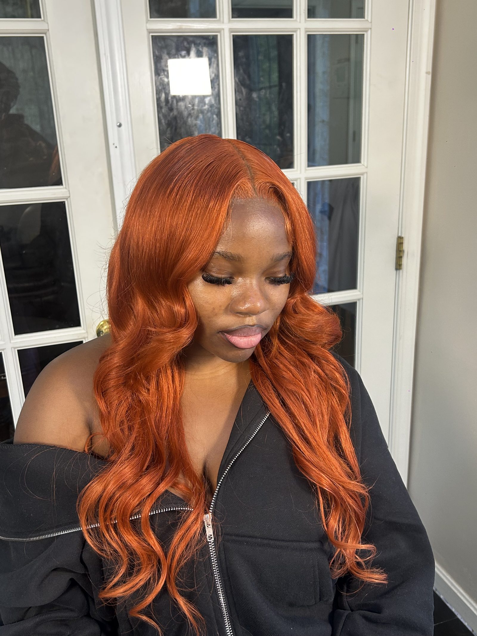 A bright copper body-wave install with a deep side parting, set into large glossy waves