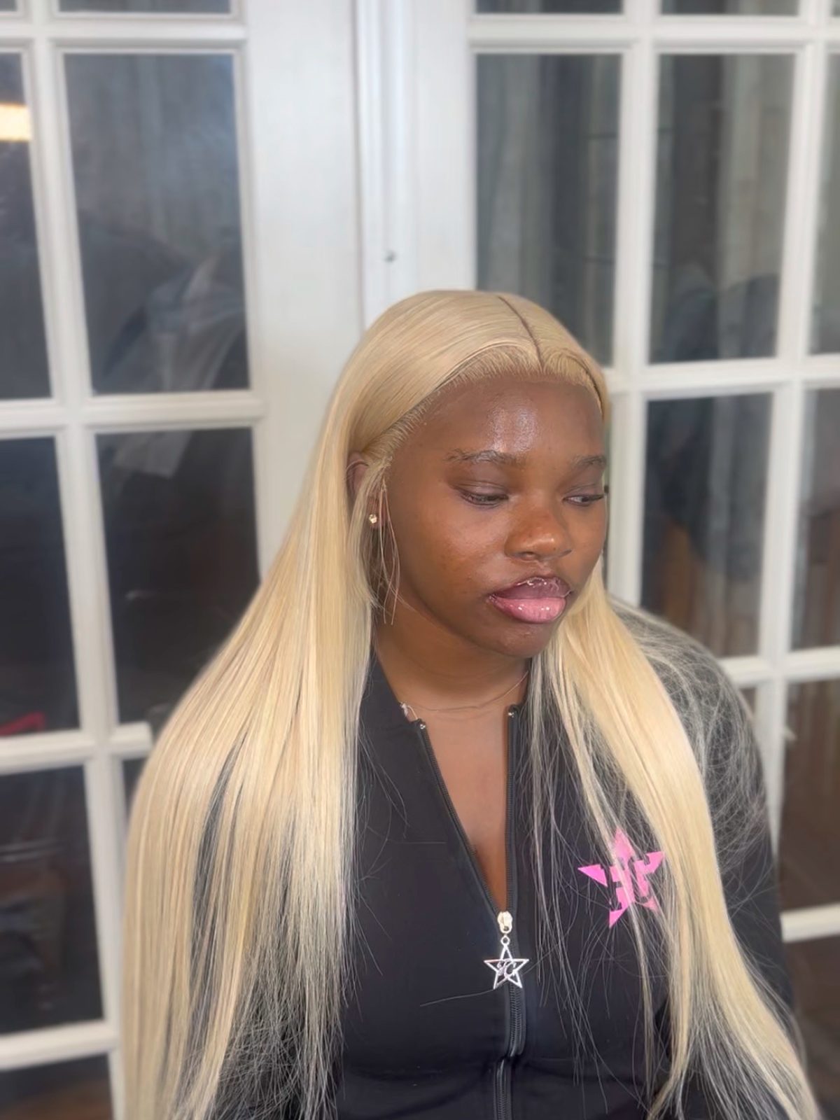 A long platinum blonde straight install parted down the middle, the lace tinted to blend away at the parting